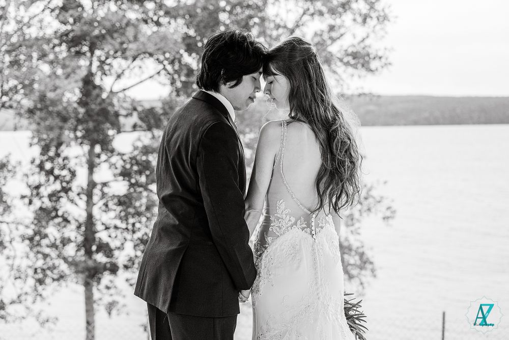 Emotional black and white wedding moment captured between couple on lakeside deck.