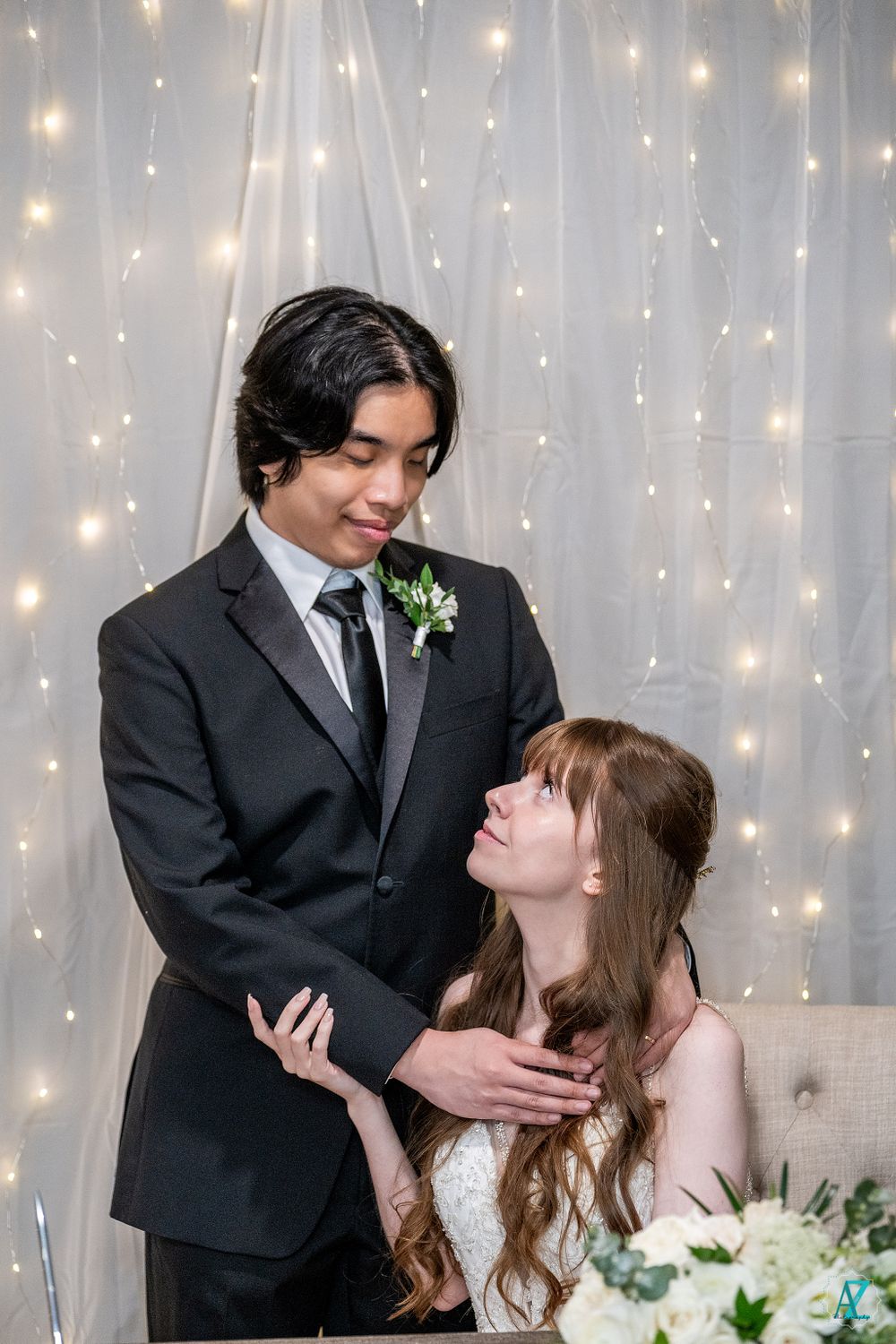 Romantic wedding portrait with twinkle light backdrop captures tender moment between couple.