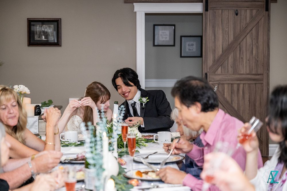 Guests gathered around a dining table at a wedding reception with drinks and place settings.