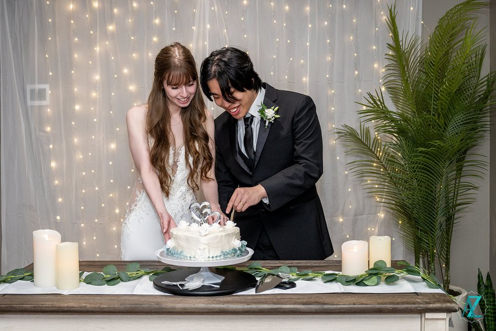 Newlyweds sharing a moment while cutting their wedding cake surrounded by candles and twinkle lights.
