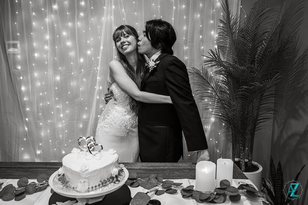 Black and white photo of a romantic cake cutting moment at a wedding reception.