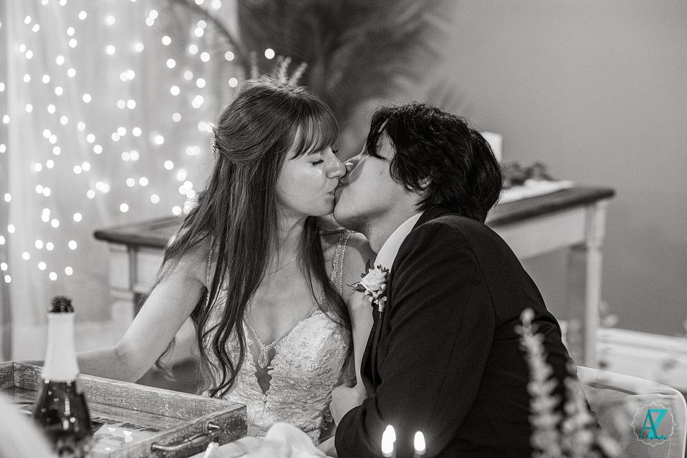 Black and white romantic wedding moment in front of twinkling lights and decor.