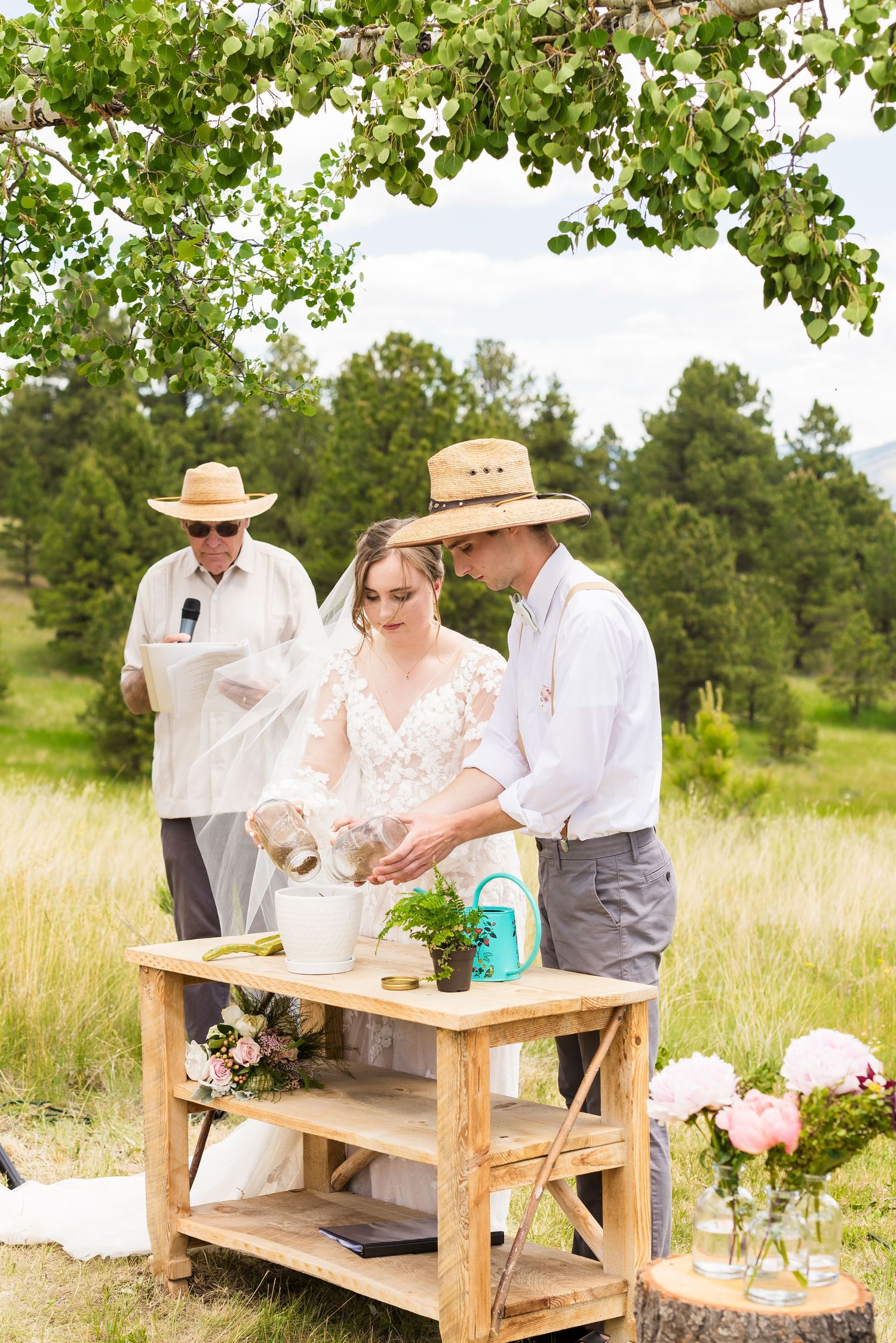 Couple participates in outdoor wedding ceremony with wooden table and floral decorations.