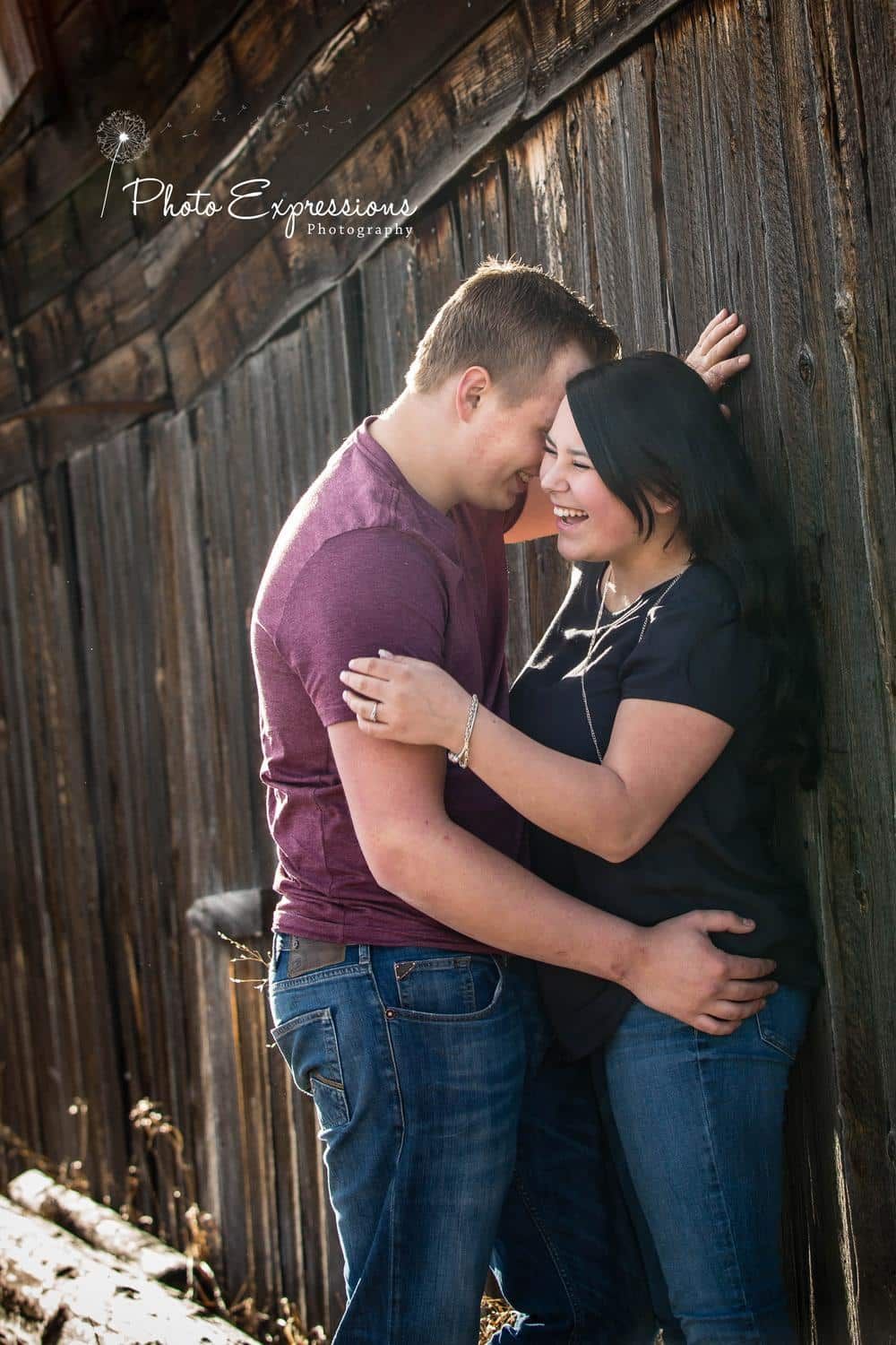 Intimate couple photoshoot against rustic wooden barn wall.