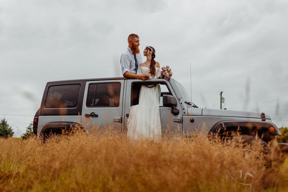 Rustic wedding portrait with silver Jeep Wrangler in golden field.