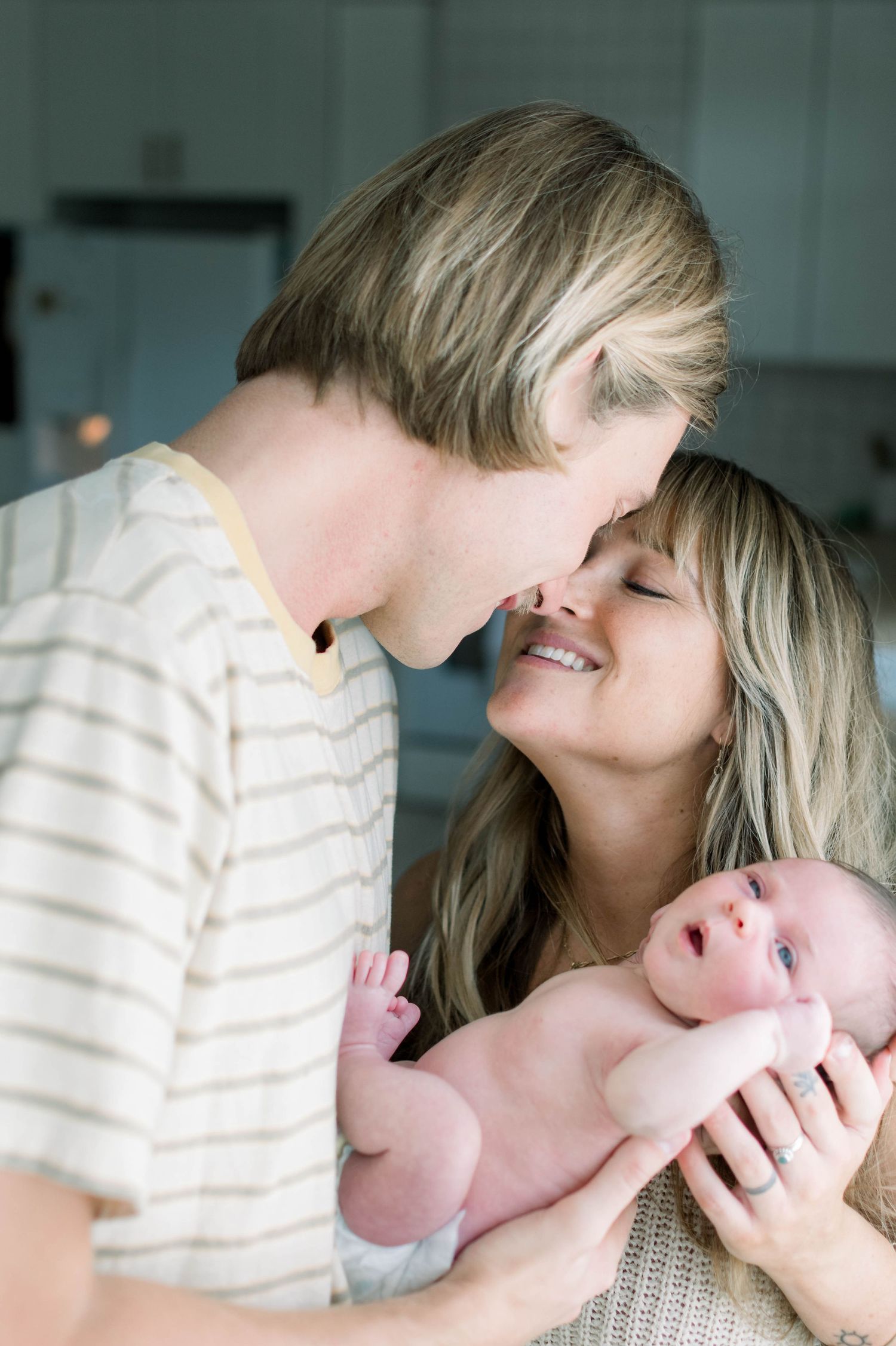 Intimate family moment with newborn baby in soft natural lighting.