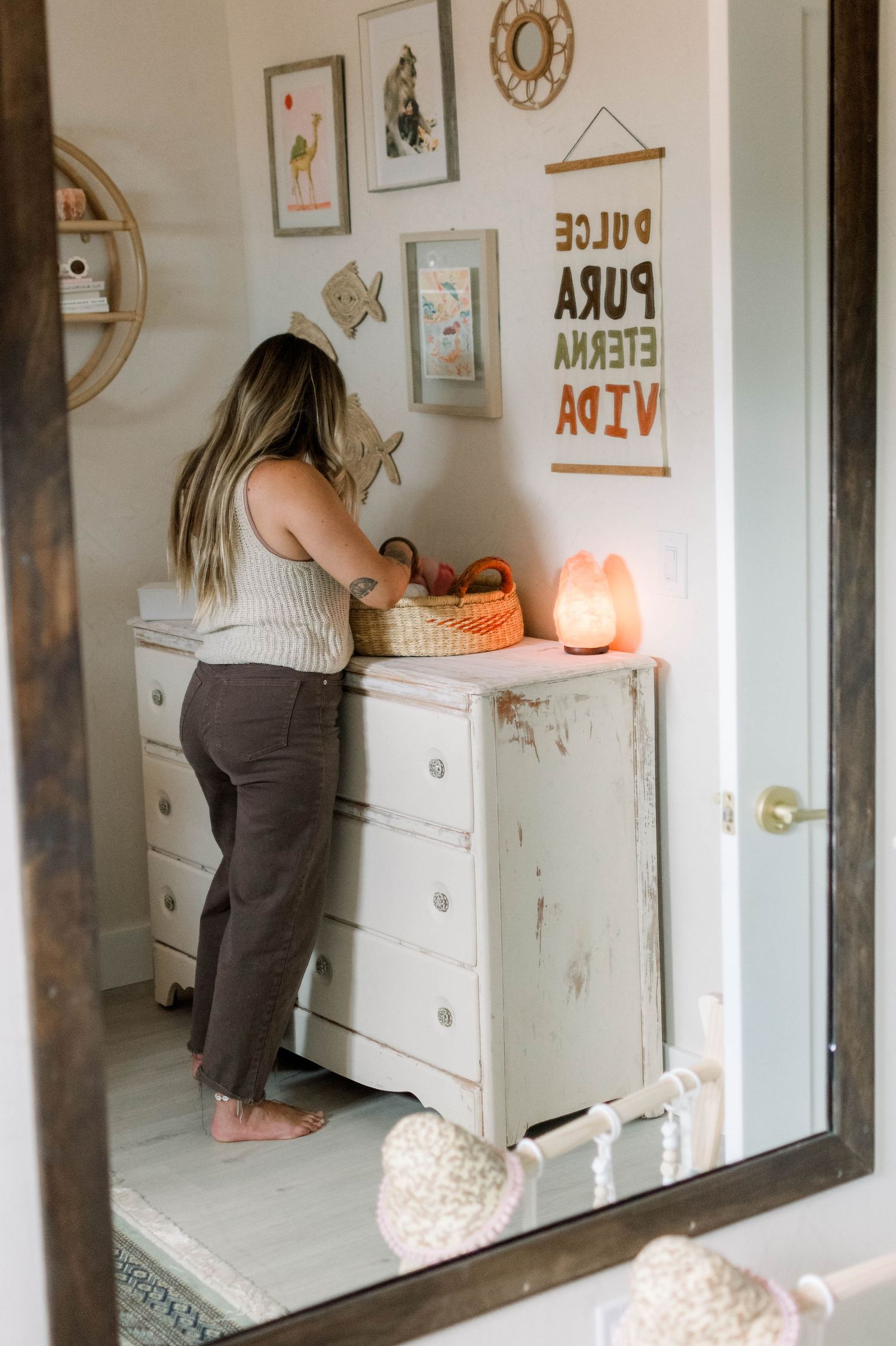 Nursery room interior with white dresser, wall art, and soft lighting.