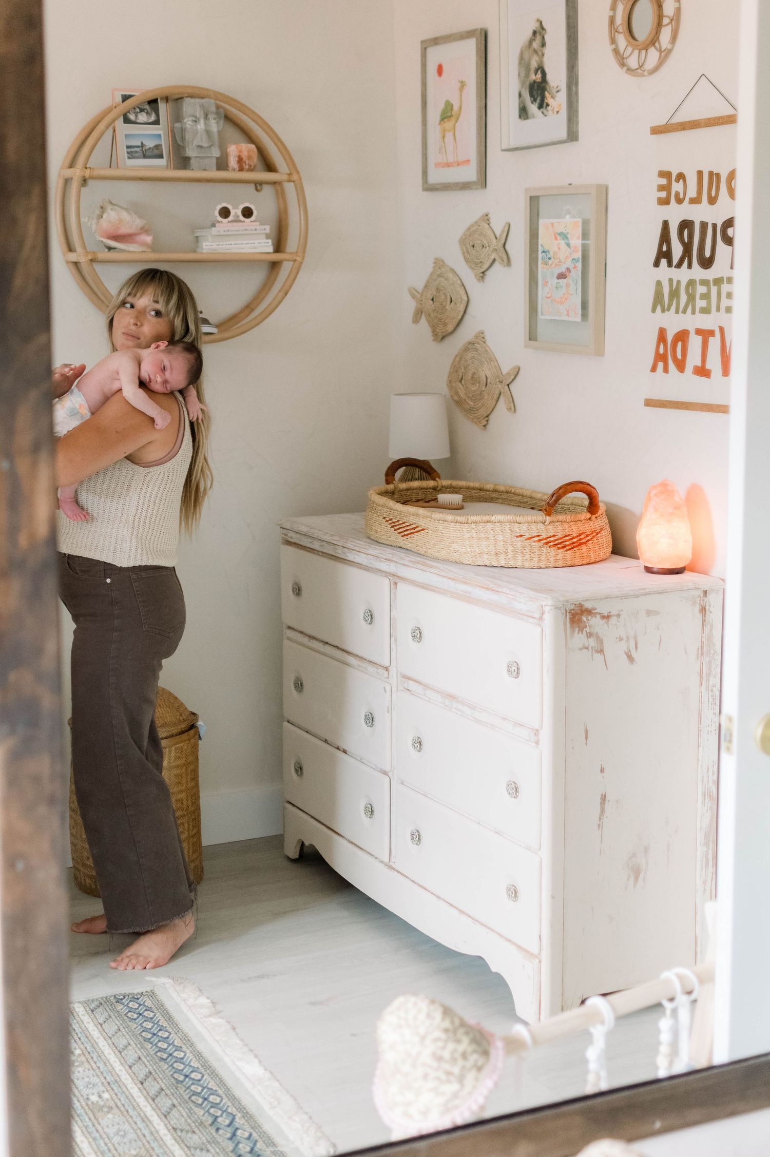 Cozy nursery corner with white dresser, circular shelf, and coastal-themed wall decor.