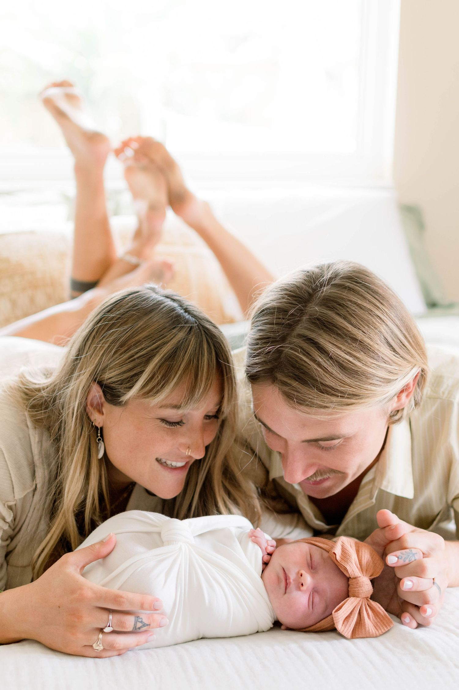 Lifestyle newborn photography on white bedding captures intimate family moments.