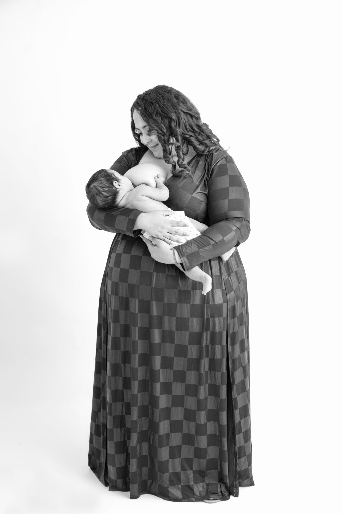 Retrato en blanco y negro de un tierno momento donde mamá tiene un intimo encuentro único con su bebe sobre un fondo blanco.