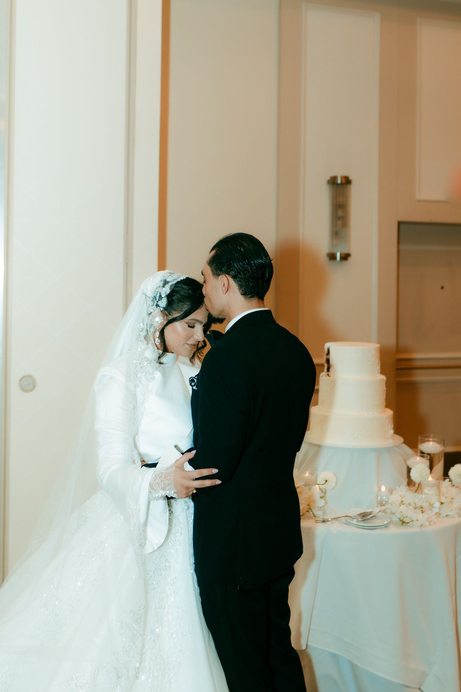 An intimate wedding moment beside an elegant white tiered cake.