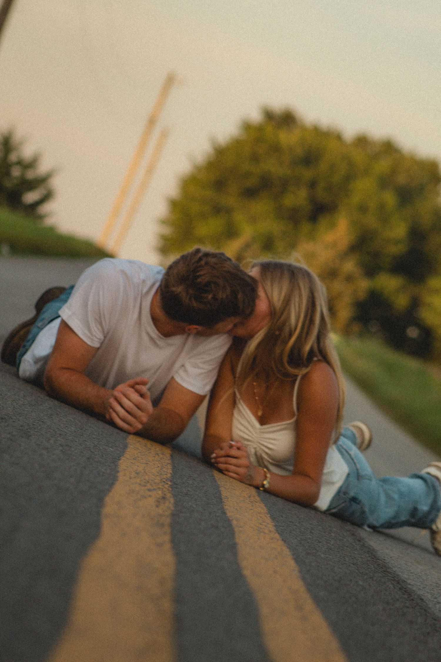 a couple laying in the middle of the road kissing
