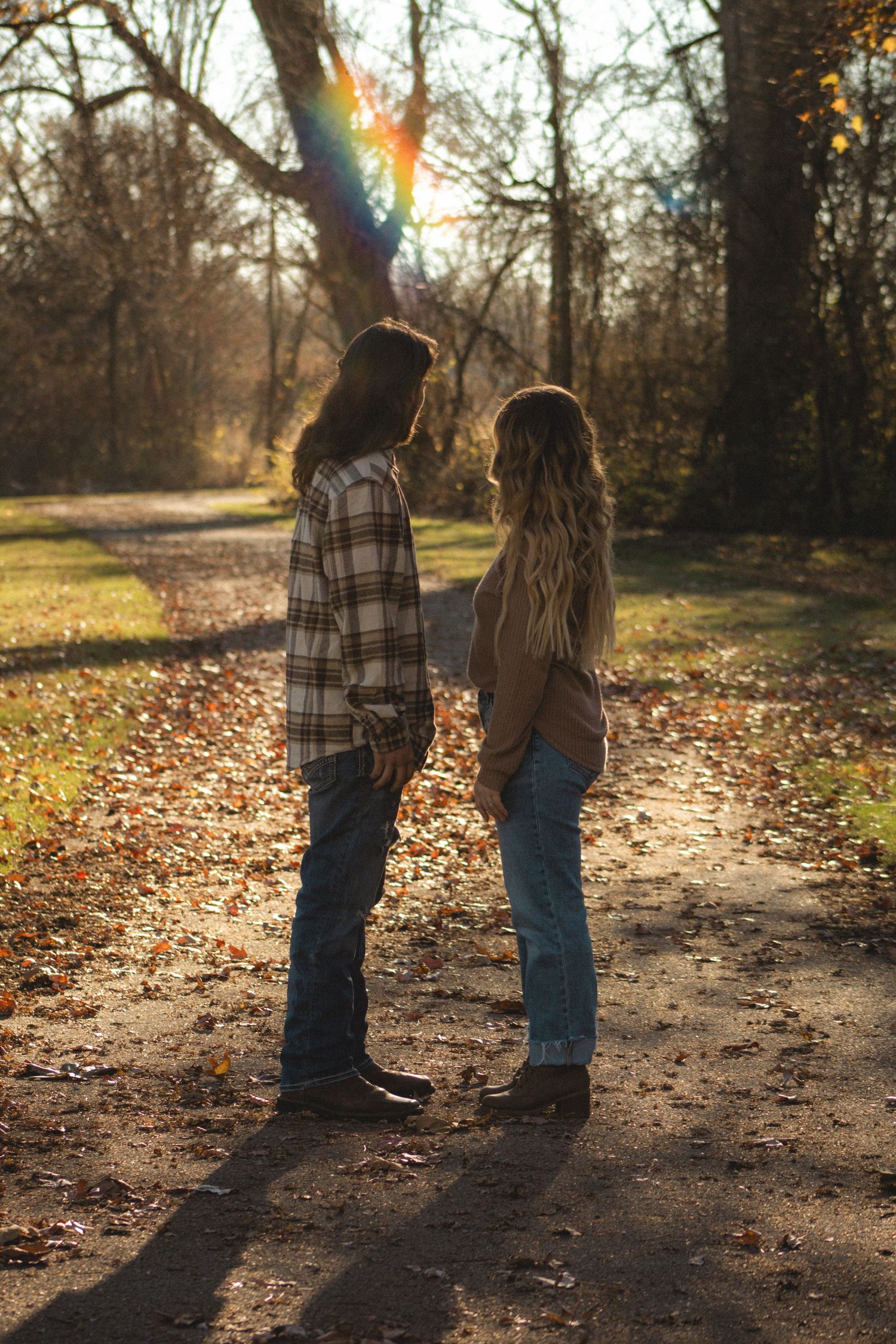 a couple standing in front of each other in the middle of the park