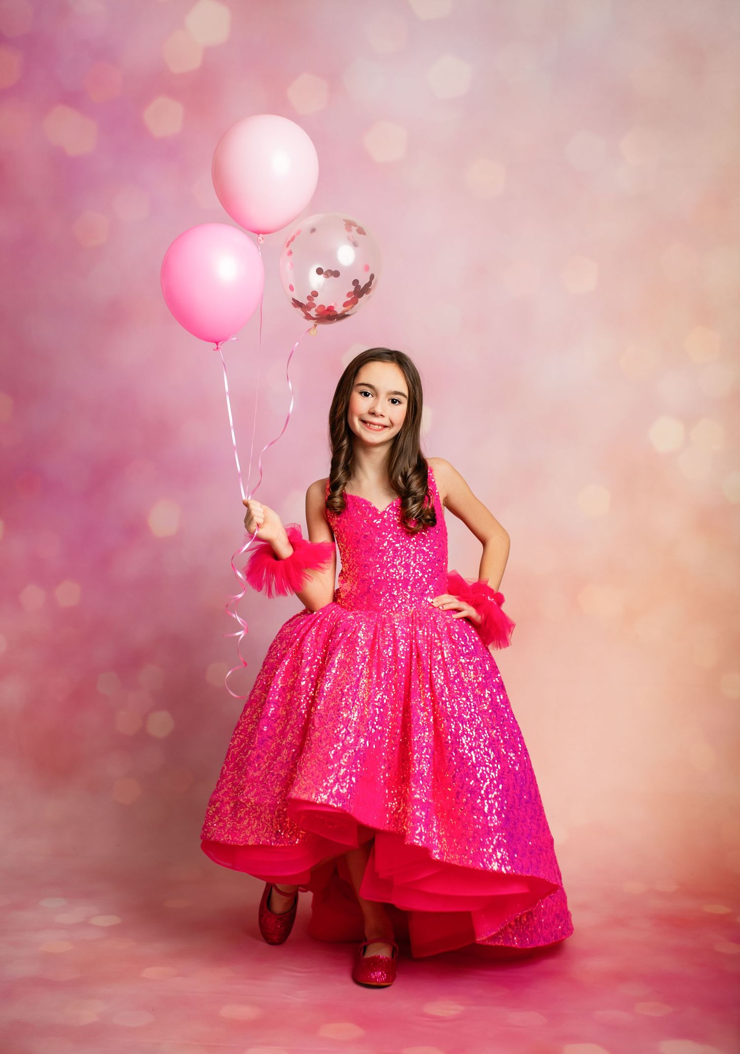 Sparkling pink high-low gown with balloons against a dreamy bokeh backdrop for a special celebration photoshoot.