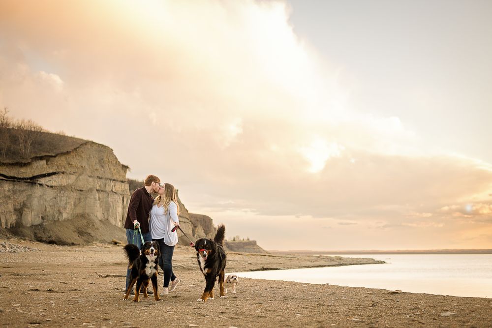 A group walking along a beach at sunset with dramatic cliffs in the background.
