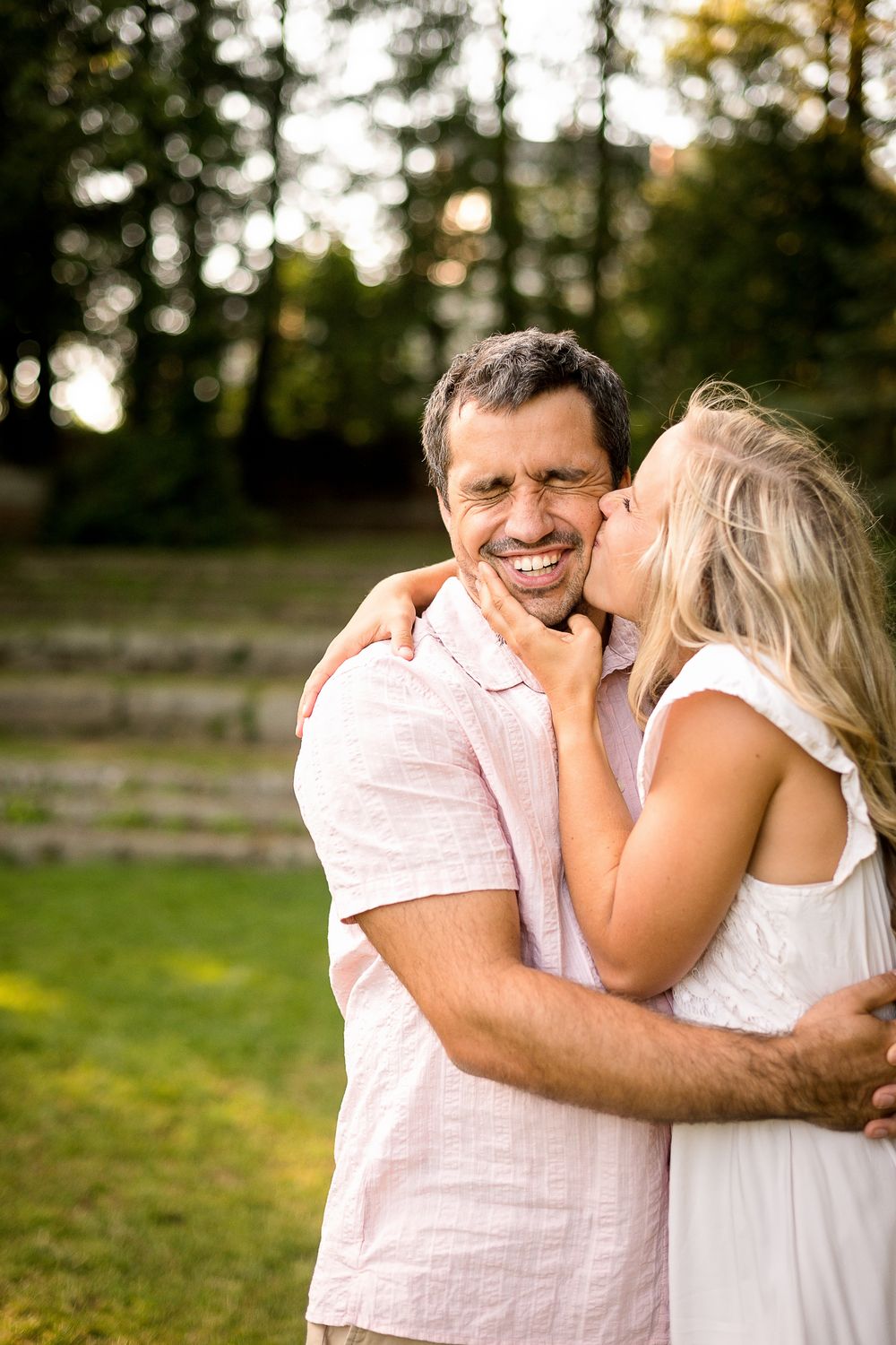 Romantic couple sharing intimate moments and laughter in a park setting.
