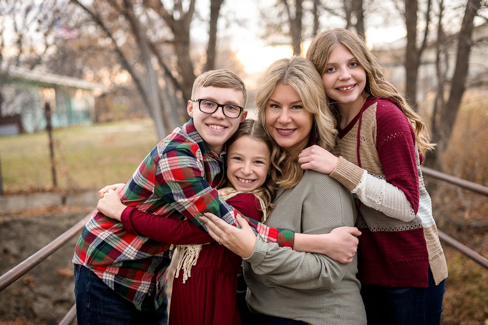 Family group hugging and laughing together outdoors in casual clothing.