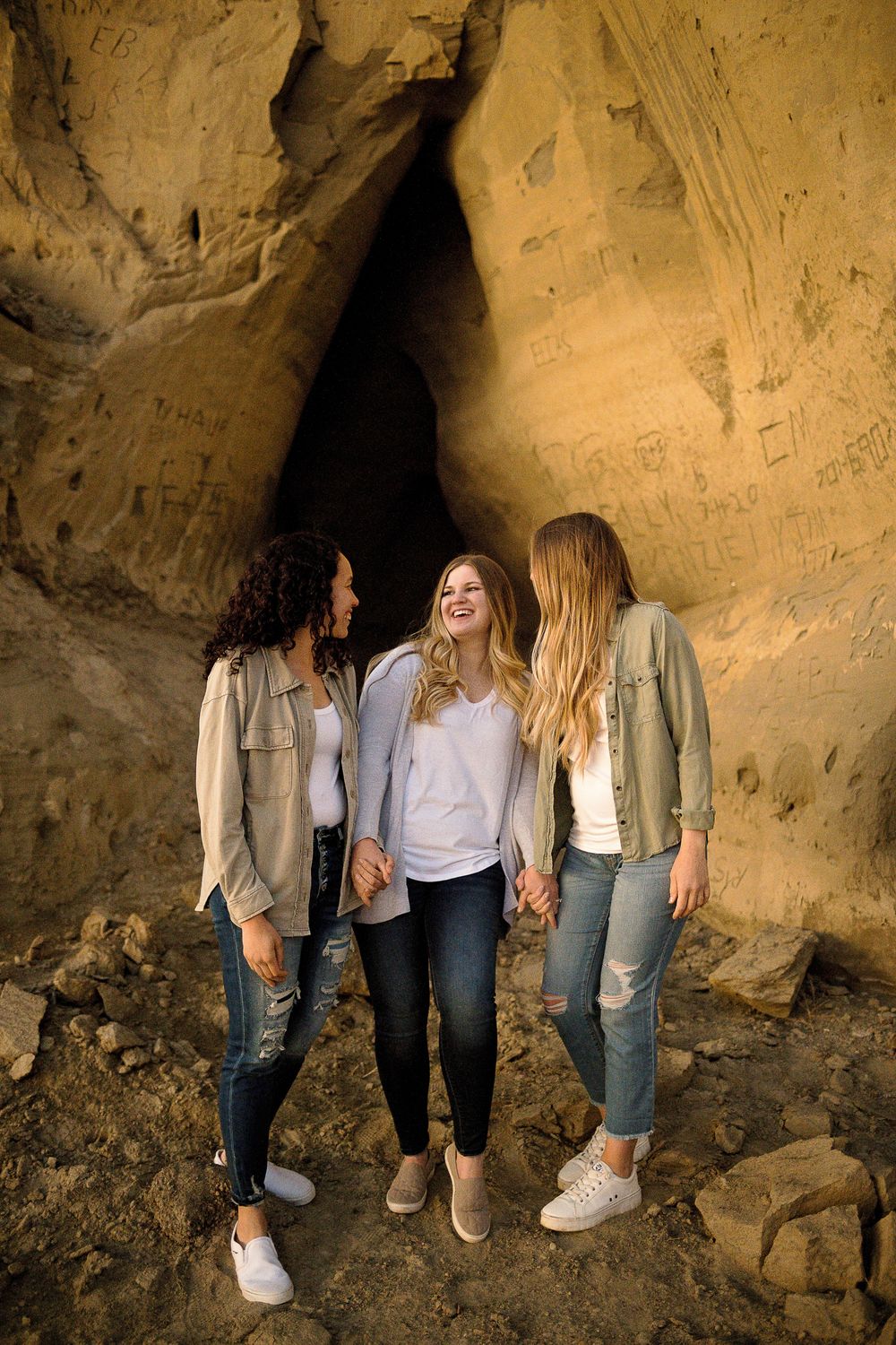 Friends exploring a natural cave formation with rocky walls and sandy ground.