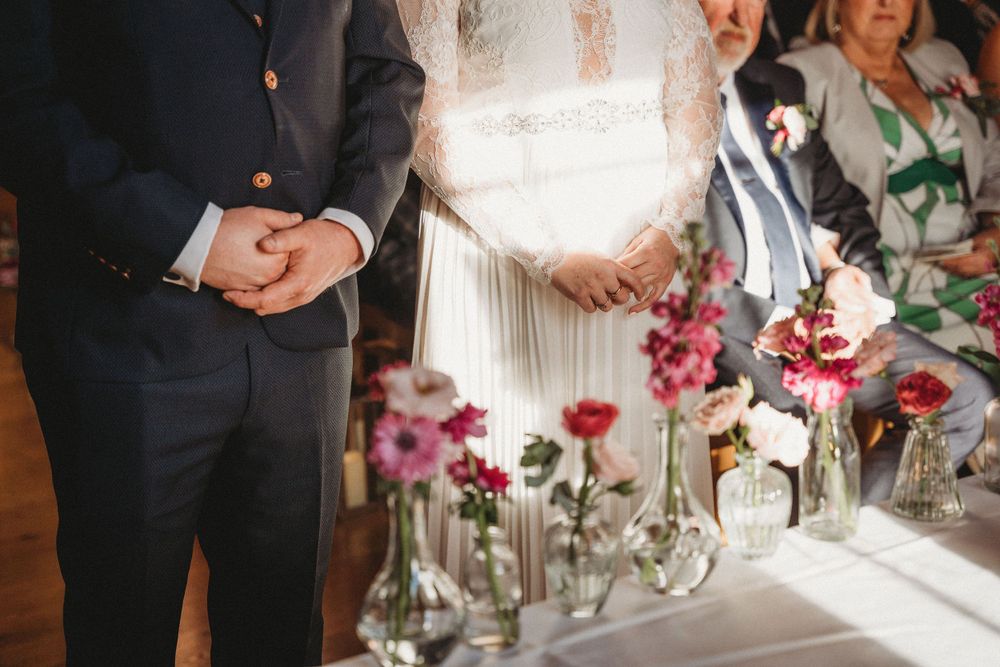 Wedding reception table decorated with pink flowers and elegant glassware in a romantic setting.
