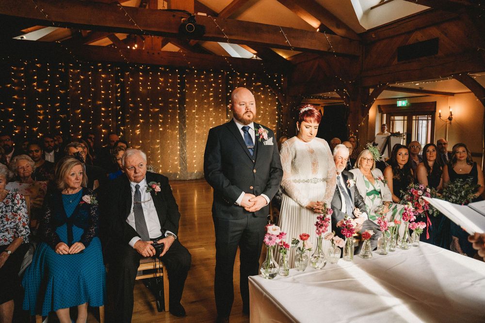 Wedding reception in progress at rustic venue with string lights and floral table decorations.