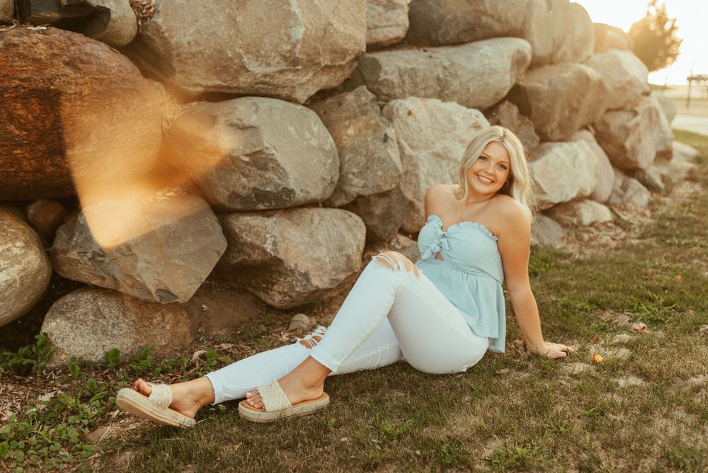 A summer evening portrait by large rocks with warm sunlight and green grass.