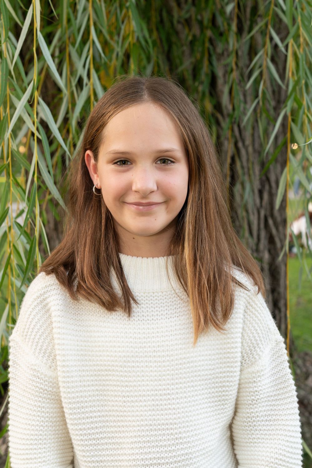 Three similar photos show a young person in a white knit sweater standing in front of a willow tree.
