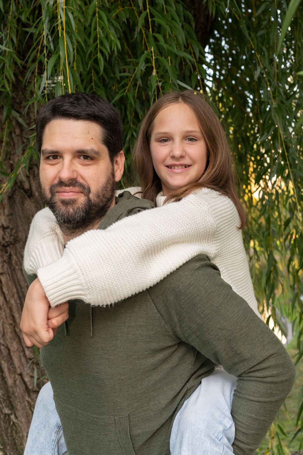 A series of candid embrace photos showing affection and connection against a backdrop of green willow tree branches.