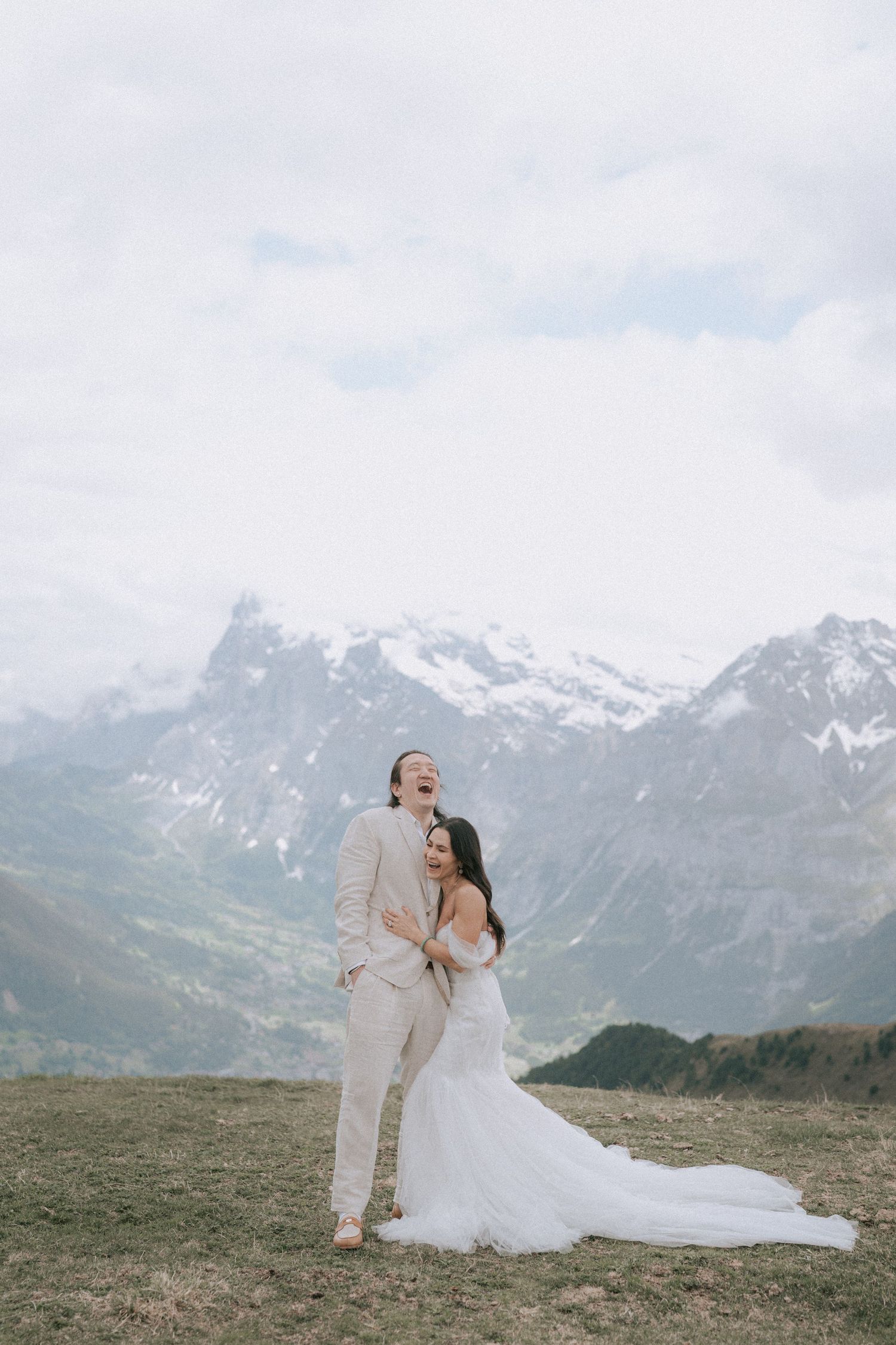 Newlyweds sharing a romantic moment against dramatic mountain peaks.