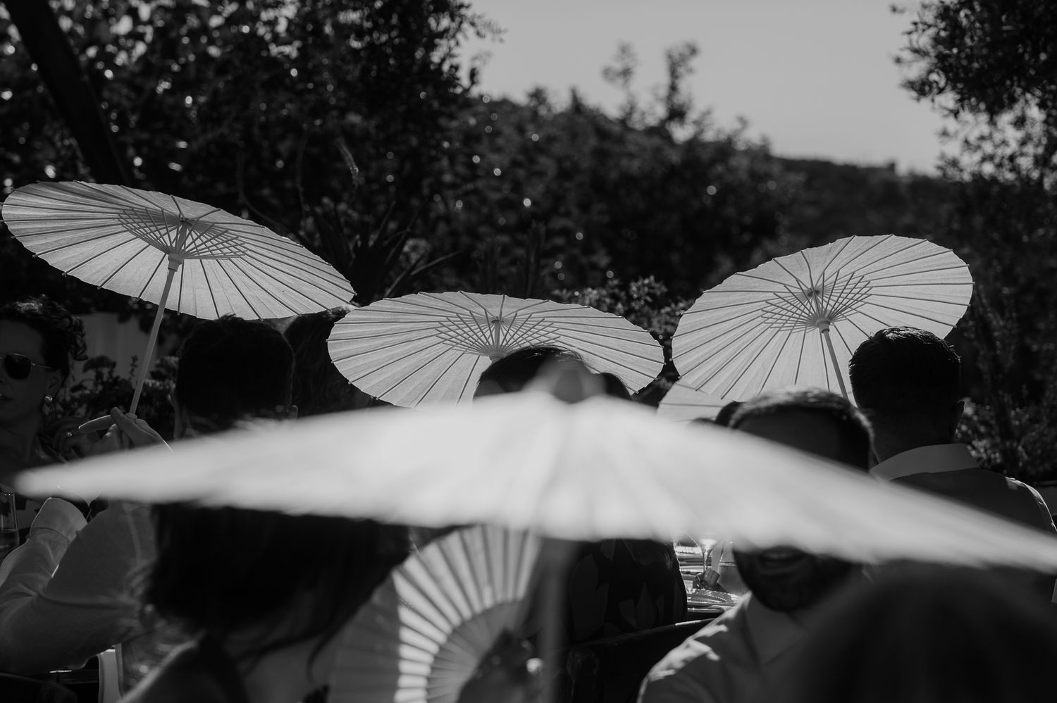 An artistic photo of guests with paper umbrellas at a wedding in Crete Greece
