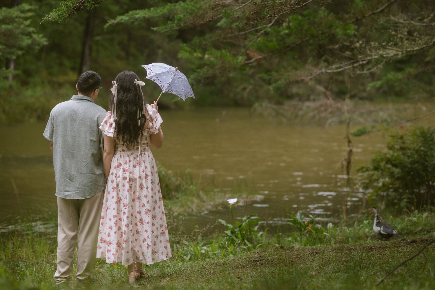 A romantic picnic scene by a lake with red flowers and vintage-style decor.