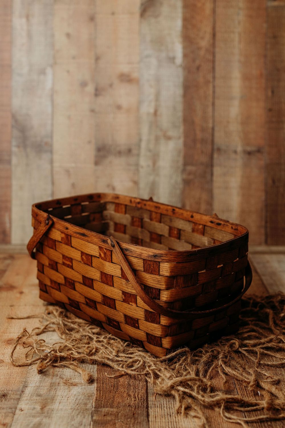 Three rustic woven wooden baskets sit on a weathered wooden surface with straw scattered around them.