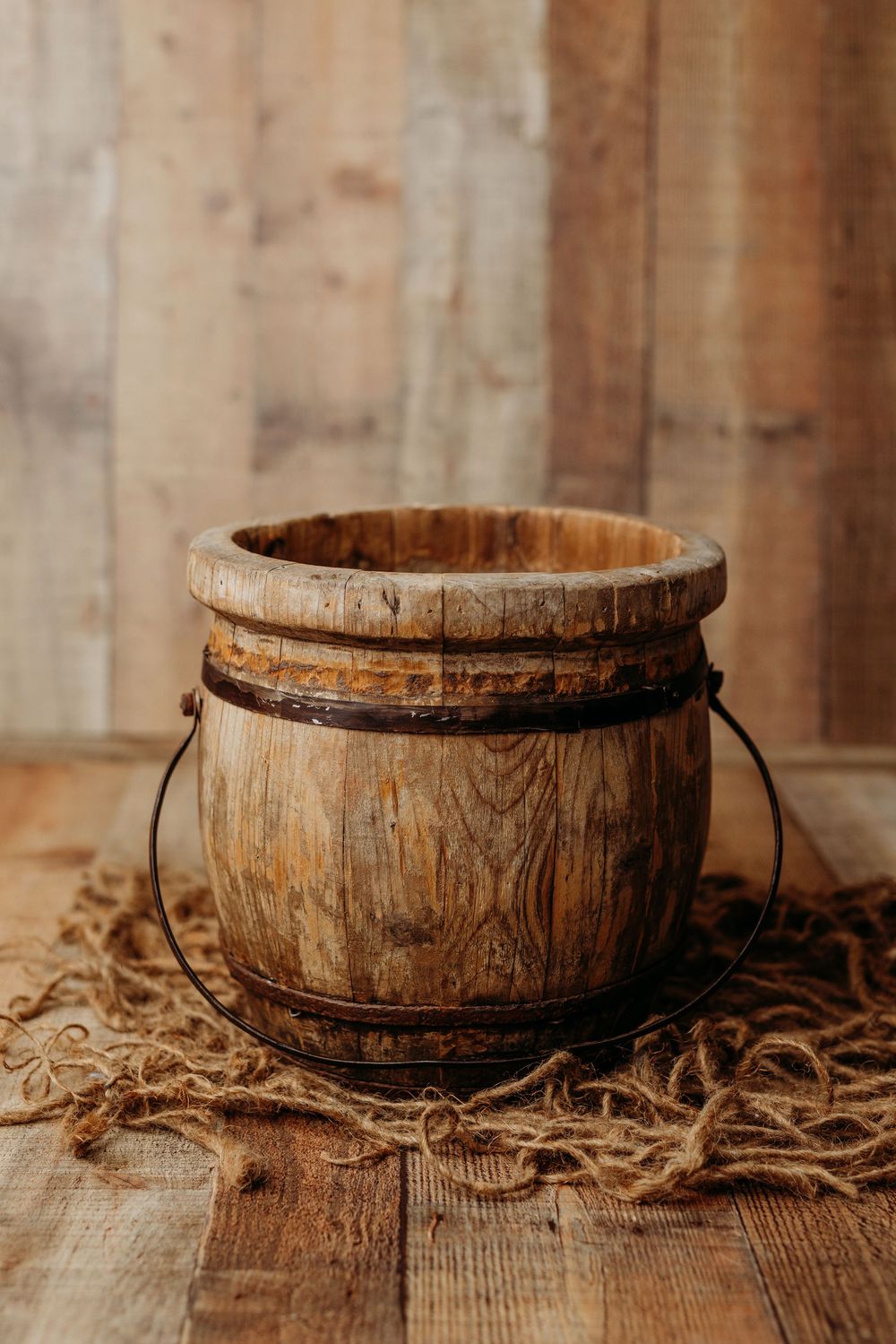 Rustic wooden bowl with textured grain sits on weathered wood surface surrounded by twine rope details.