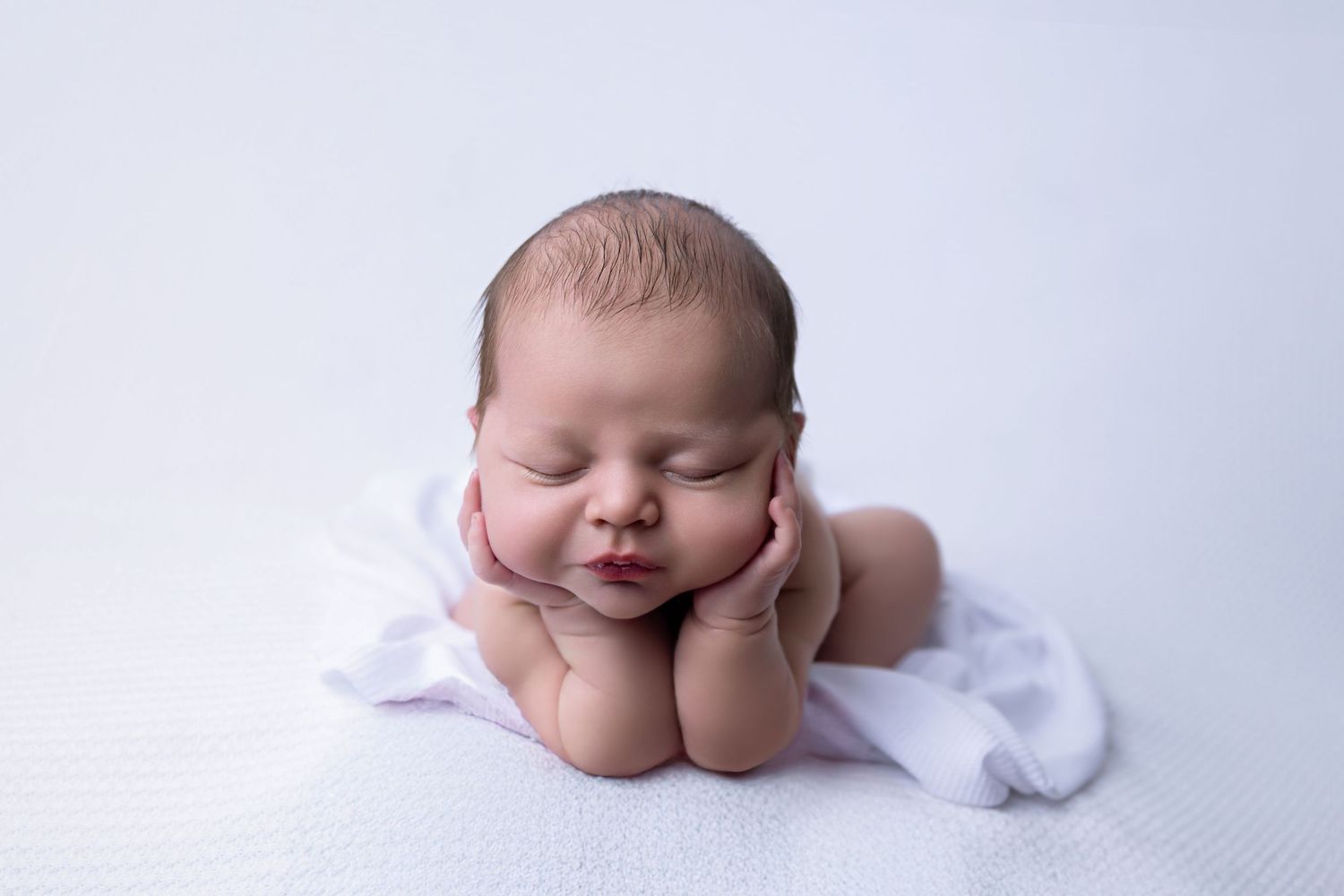 Peaceful sleeping newborn baby nestled on soft brown fabric wearing matching headpiece in artistic portrait.