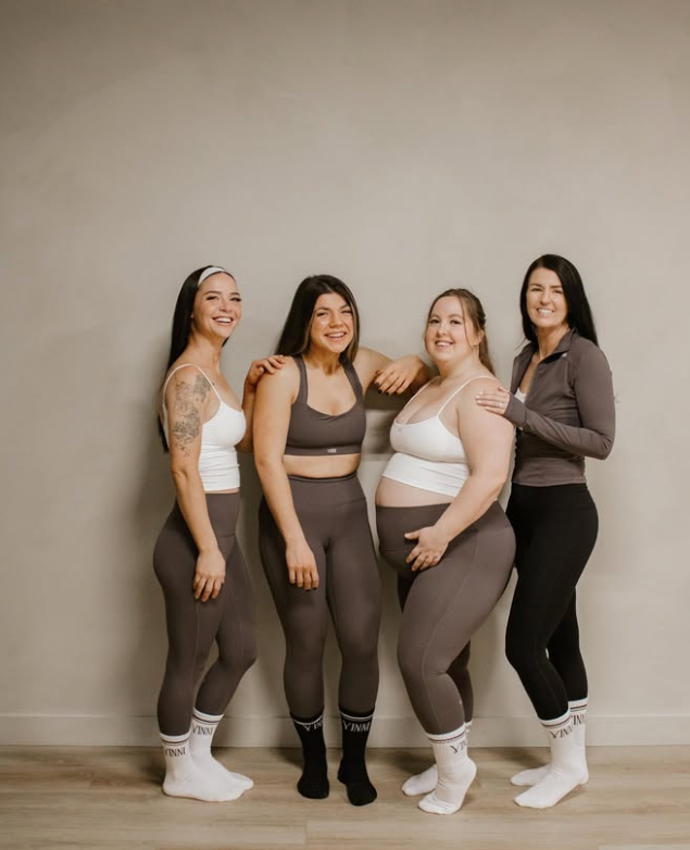 Four ladies in activewear standing together laughing.