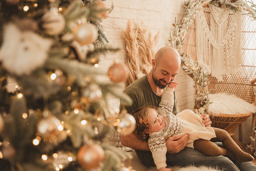 A heartwarming Christmas scene with people playing near a decorated tree with warm bokeh lighting.