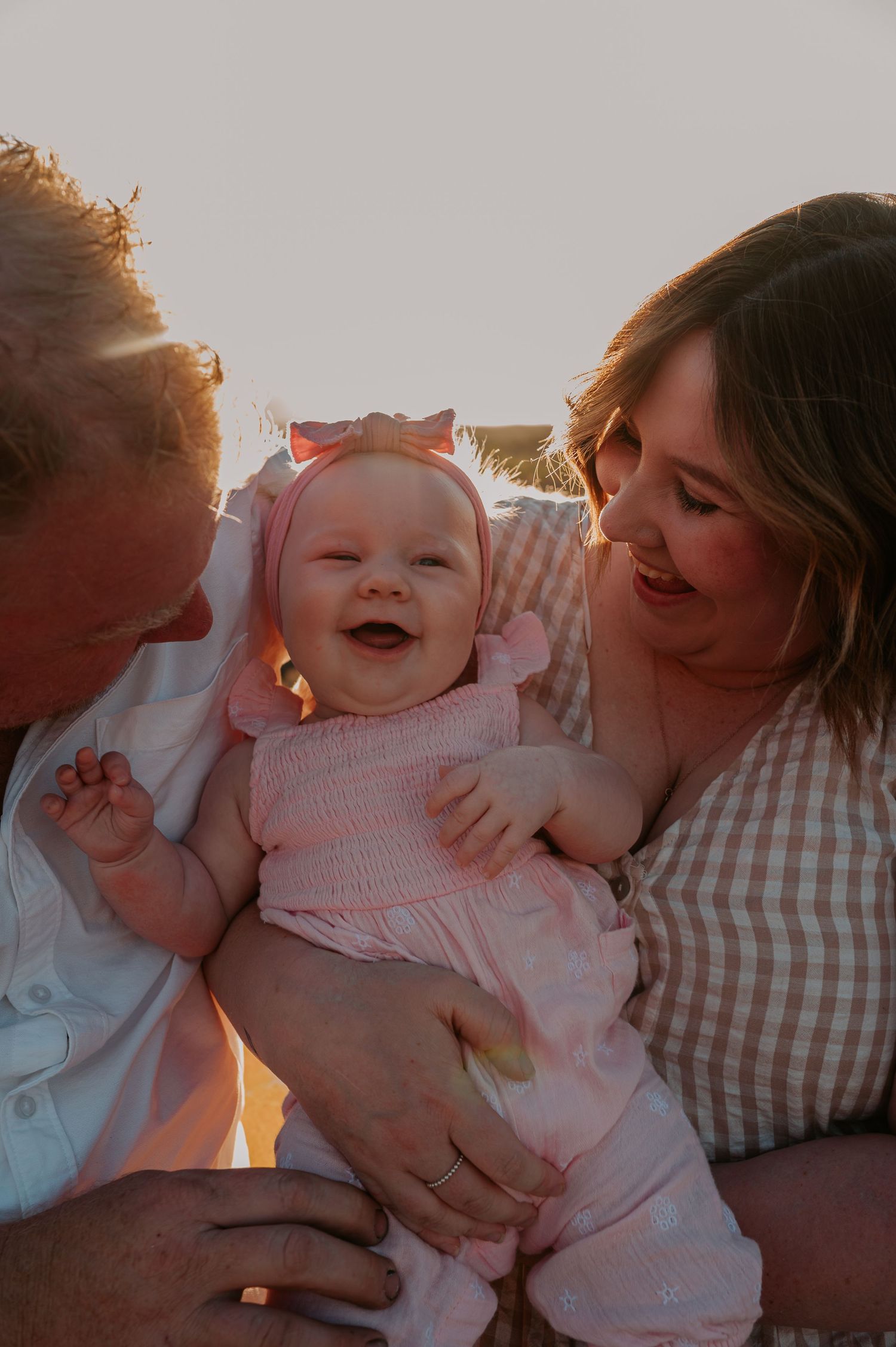 Smiling baby in between mum and dad's arms - Alice Springs
