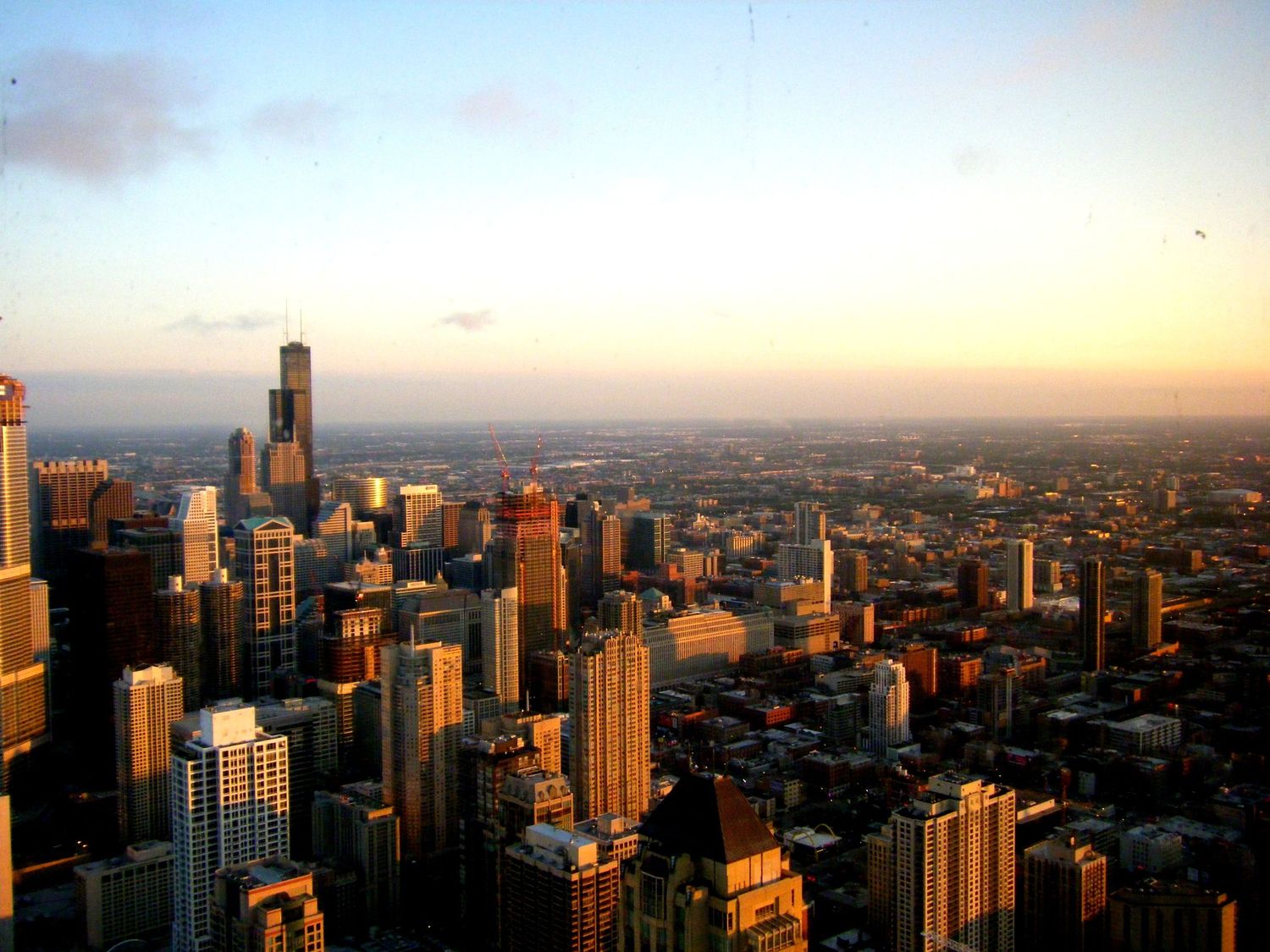 Golden sunset illuminates Chicago's towering skyscrapers in warm light.