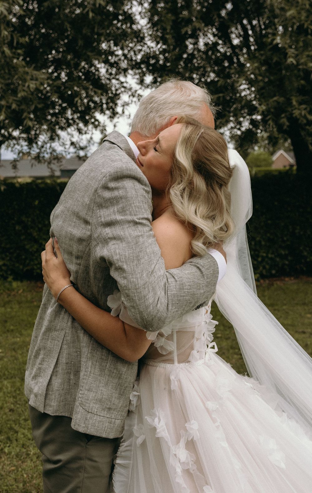 Romantic wedding moment captured outdoors with flowing white dress and veil.
