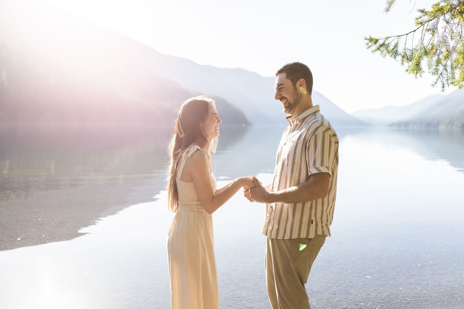 Romantic couple enjoying sunset by mountain lake in dreamy lighting.