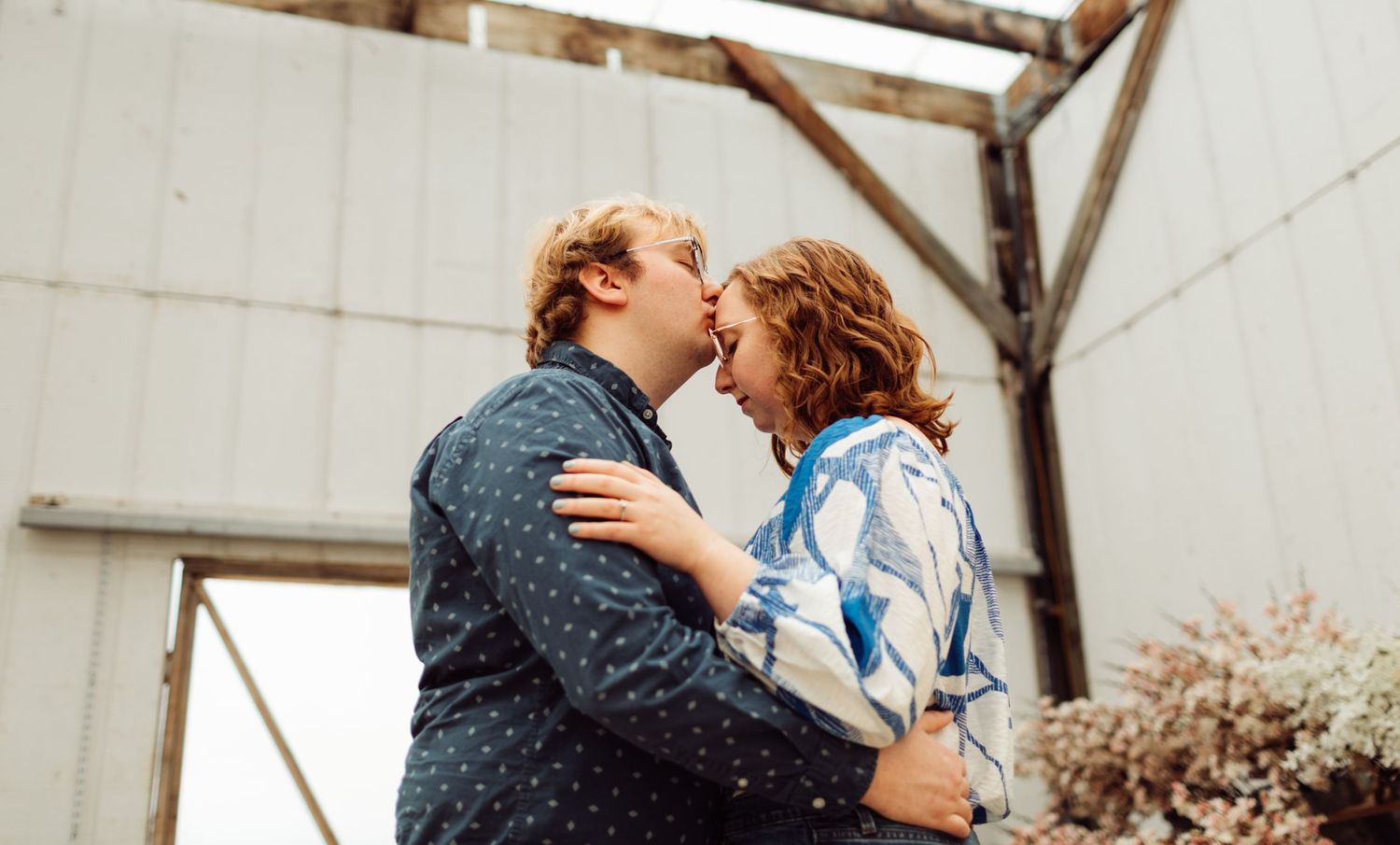 Happy young couple laughing and embracing each other outdoors near weathered white building.