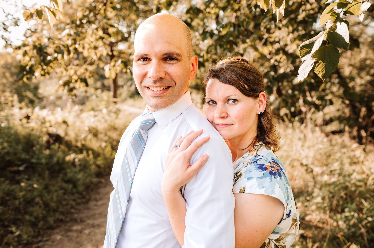 Couple posing back to back among golden autumn foliage in a romantic outdoor portrait.