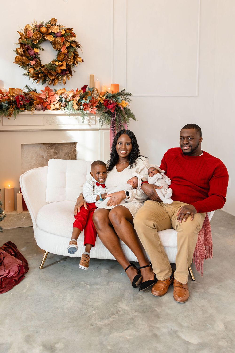 Joyful Black family with two children posing on a white sofa with festive autumn holiday decor.