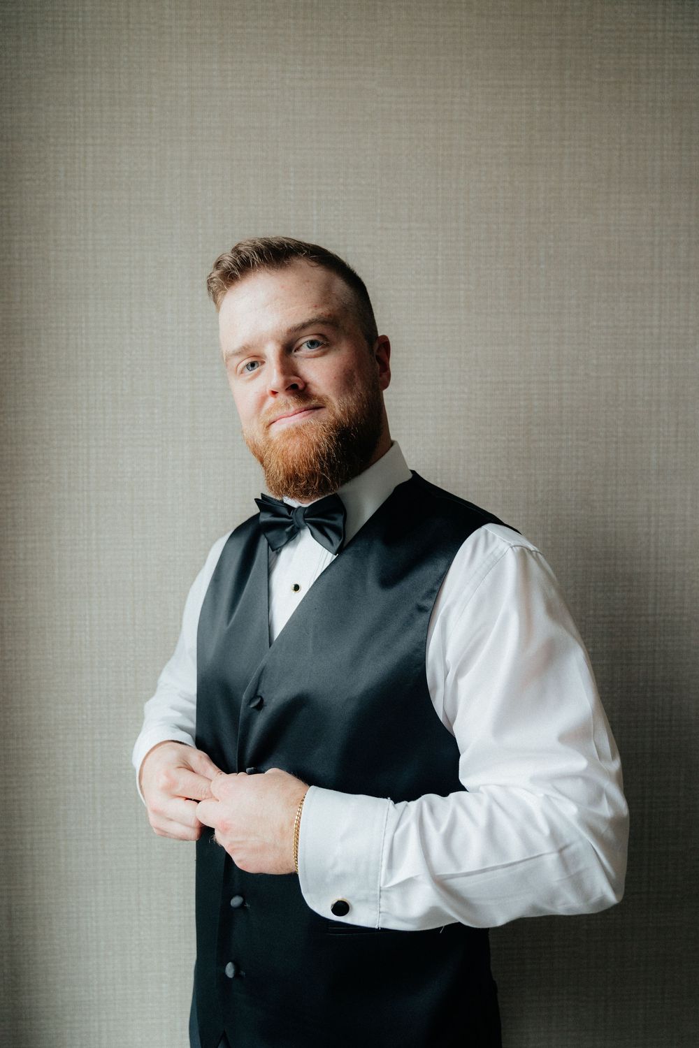 Portrait series of groomsman in formal attire posing against grey wall.