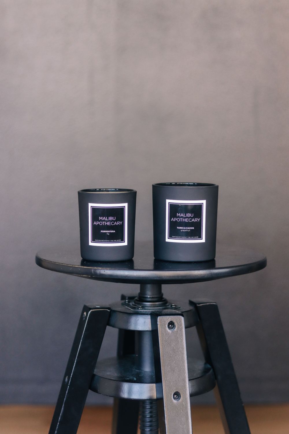 Black candles arranged on dark wooden tables in a minimalist setting.