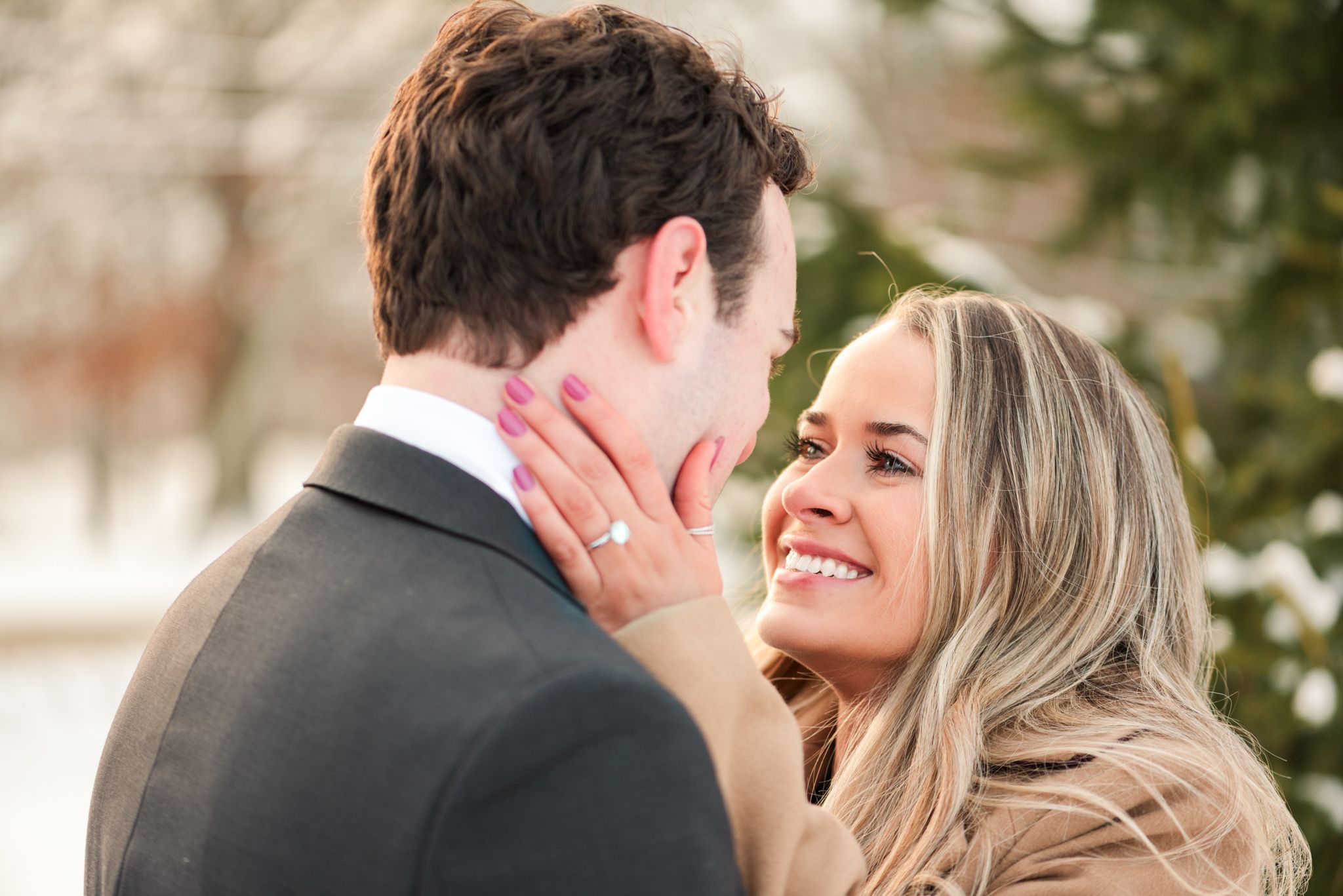 A romantic couple sharing an intimate moment outdoors with the woman gently touching her partner's face and smiling.