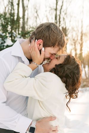 A romantic winter wedding photo series showing a couple embracing and kissing in a snowy outdoor setting.