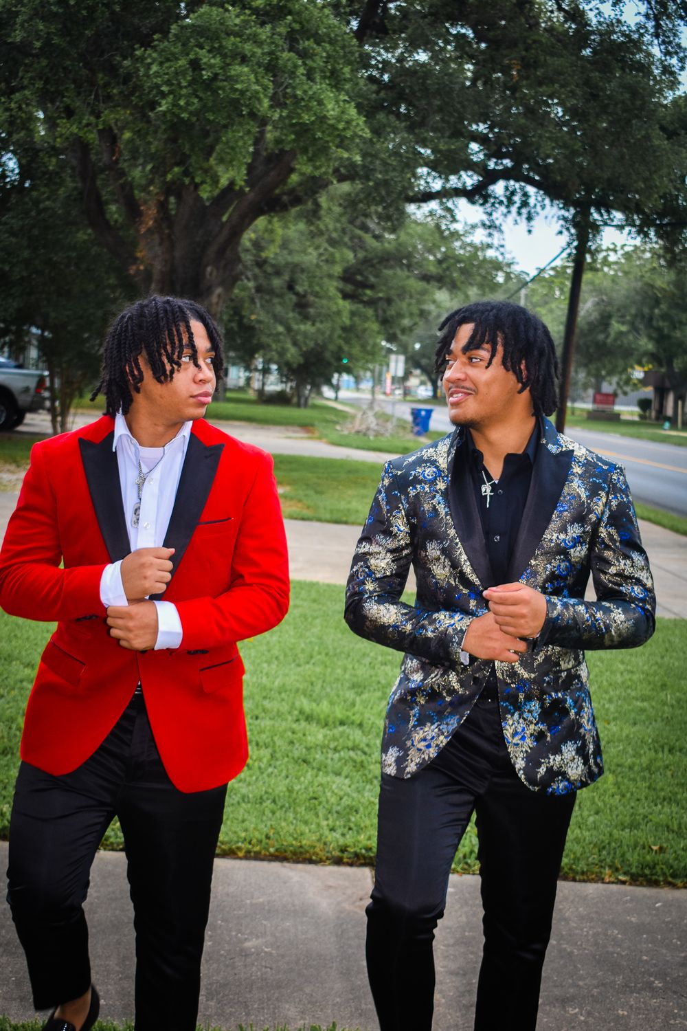 Two people in formal blazers having conversation outdoors, one in red and one in floral print.