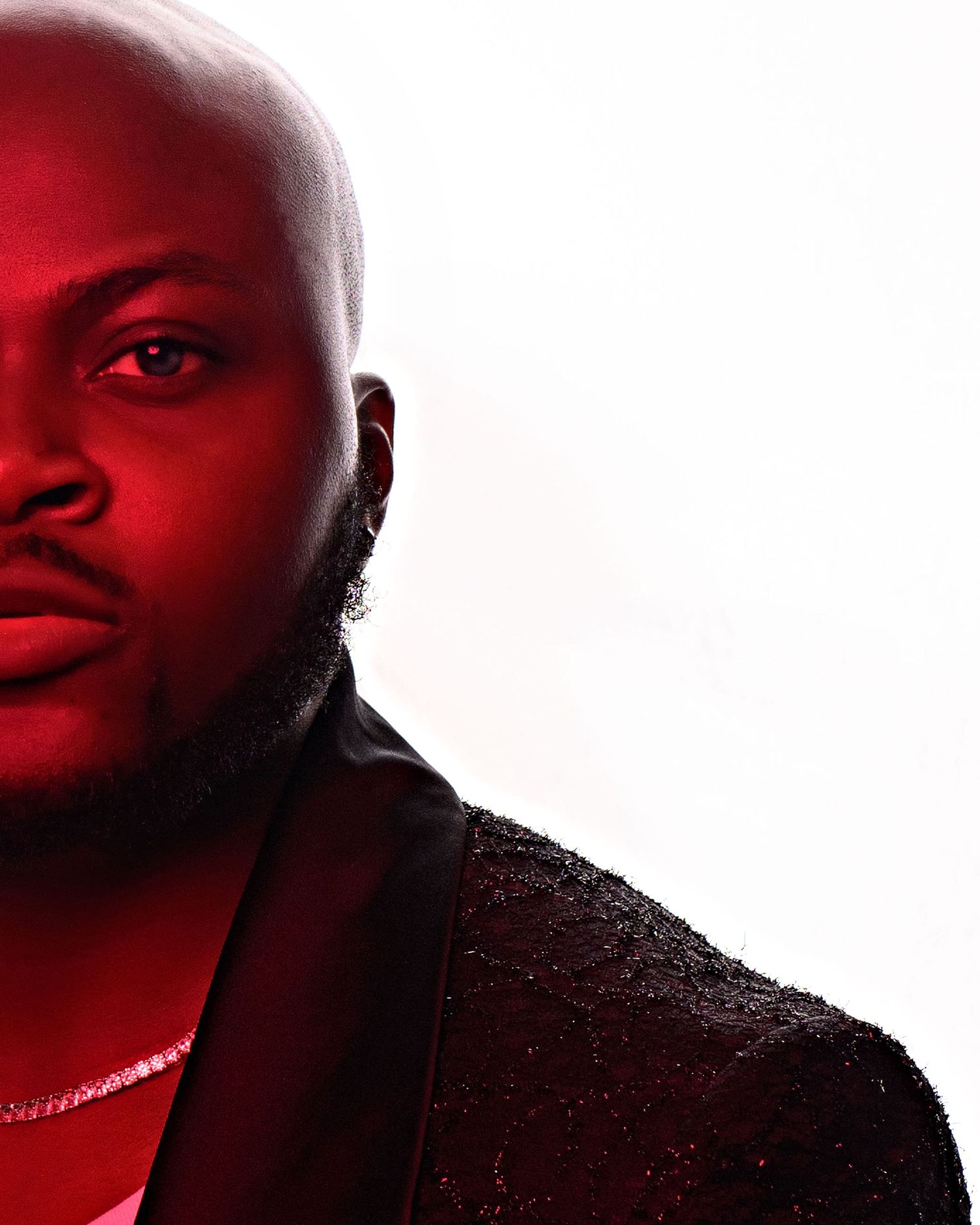 Dramatic portrait with red lighting highlighting facial features against white background.