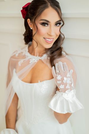Beautiful bridal portrait featuring delicate lace details, white gloves with floral appliques, and a red hair accessory.