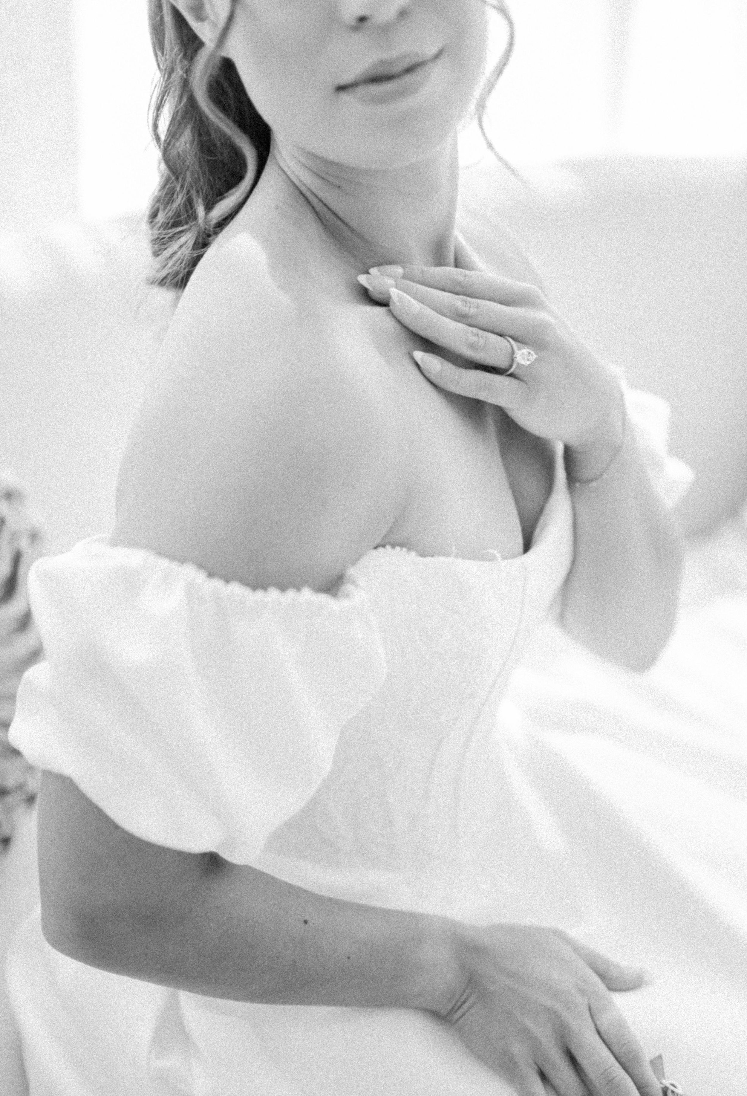 Ethereal bridal portrait featuring delicate off-shoulder gown with ruffled neckline in soft natural light.